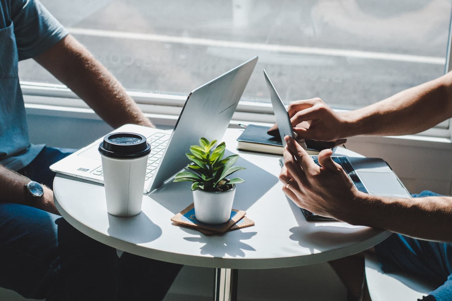 A workspace with a laptop, coffee, and a plant